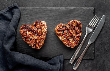 Two cakes with nuts in the shape of a heart for valentine's day on a stone background