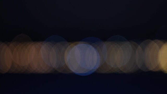 View Punta del Este lights out of focus at dusk, seen from Mansa Beach during a warm sunset. Punta del Este lighthouse can be seen in the middle of the frame.