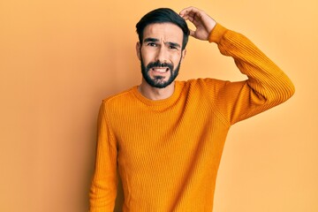 Young hispanic man wearing casual clothes confuse and wonder about question. uncertain with doubt, thinking with hand on head. pensive concept.