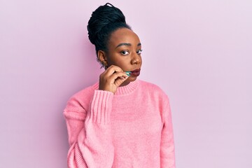 Young african american woman wearing casual winter sweater mouth and lips shut as zip with fingers....
