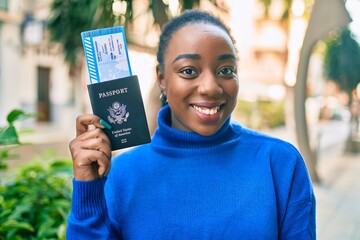 Young african american woman smiling happy holding usa passport and boarding pass at the park.