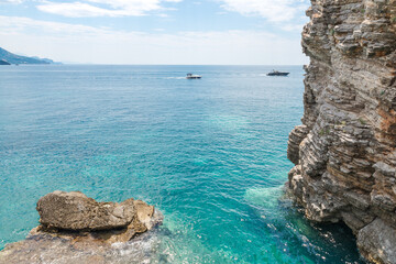 Naklejka premium Two boats near rocky steep sea coast