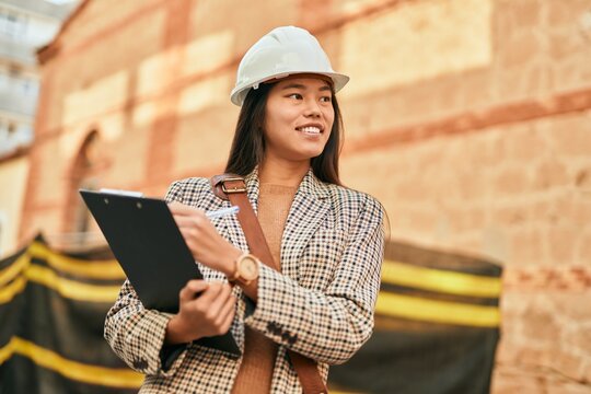 Young asian architect woman smiling happy writing on clipboard at the city.