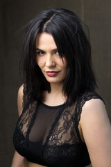 Fototapeta premium Portrait of a young sexy brunette girl in a lace top in dramatic tones. Vintage photo.