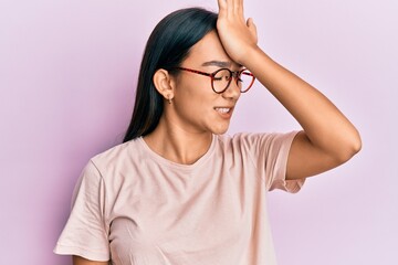 Young asian woman wearing casual clothes and glasses surprised with hand on head for mistake,...