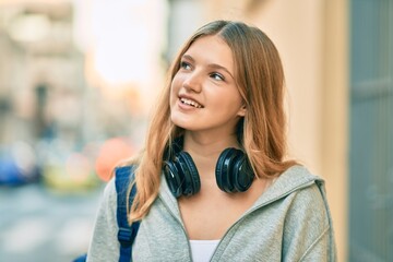 Beautiful caucasian student teenager smiling happy using headphones at the city.