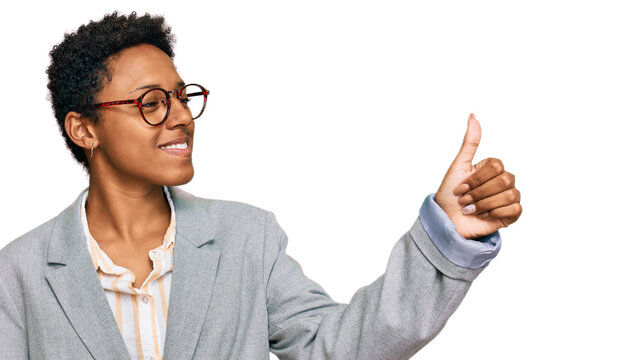 Young african american woman wearing business clothes looking proud, smiling doing thumbs up gesture to the side