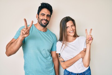 Beautiful young couple of boyfriend and girlfriend together smiling with happy face winking at the camera doing victory sign with fingers. number two.