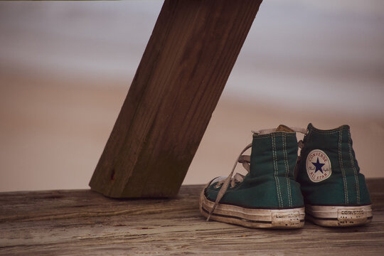 A pair of old converse tennis shoes sitting on a dock at the beach in Topsail Island, North Carolina.