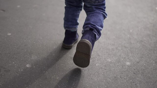 Toddler baby boy feet walking on sidewalk during winter time