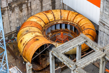 An element of the water turbine of the hydroelectric power plant lies at the dam under construction. © alexhitrov