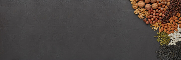 Various types of nuts and seeds on black slate background. Top view with copy space. Healthy food. Vegetarian nutrition