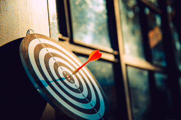 Dart arrow hit on bulleyes of dartboard to represent that the business reached the target  with...
