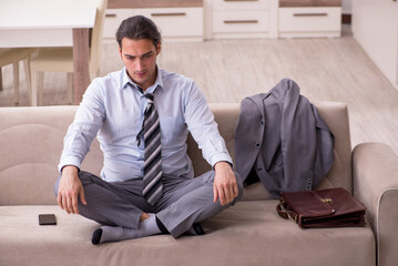 Tired young businessman coming home after working day