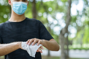 Young man wearing suricate mask and cleaning hand by wet wipes