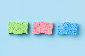 Creative layout with sponges for dishwashing on blue background.
