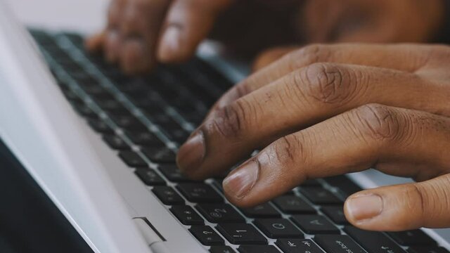Close up shot of hands of unrecognizable afro-american businessman typing on laptop keyboard. High quality 4k footage