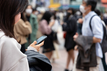 渋谷駅前でスマートフォンを見る若い女性の手元