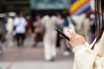 渋谷駅前でスマートフォンを見る若い女性の手元