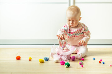 Little baby girl playing with traditional easter bread decorated with bunny ears gingerbread cookies. Creative easter cake decoration. Easter panettone. Happy little kid playing on the floor