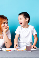 Children's creativity. mom and child son paint watercolor homework for kindergarten on blue background