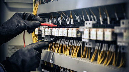 Close-up hand of electrical engineer using measuring equipment to checking electric current voltage...