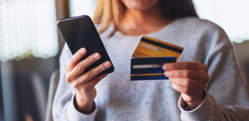Closeup image of a woman using credit card for purchasing and shopping online on mobile phone