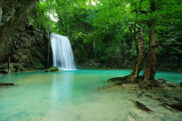 Fototapeta na wymiar waterfall clear emerald water or blue pool and pond on summer season with rock and tree roots for holiday relax travel in green jungle or forest at erawan waterfall floor 3 for nature landscape