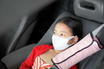 Asian child or kid girl wearing n95 white face mask in car for close mouth nose to protect pm2.5 dust smoke or covid coronavirus and vacant sit with wearing seatbelt or safety belt on seat for travel