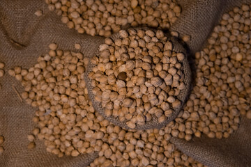 top view of chickpea in antique sack. Uncooked Dry chickpeas in sack isolated on burlap background. Grains are scattered out of the bag. Heap of legume chickpeas background with sackcloth