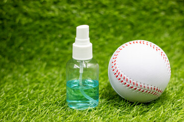Baseball with hand sanitizer are on green grass for covid preventiion