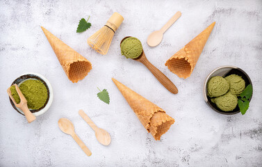 Fototapeta na wymiar Matcha green tea ice cream with waffle cone and mint leaves setup on white stone background . Summer and Sweet menu concept.