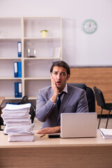 Fototapeta premium Young male employee unhappy with excessive work in the office