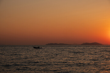 Fototapeta na wymiar A boat glides across the waters of South China Sea during the sunset