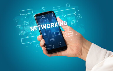 Female hand typing on smartphone with NETWORKING inscription, social media concept