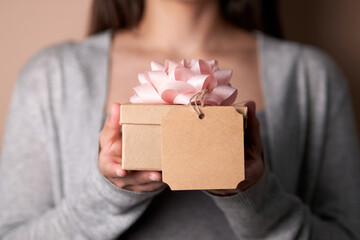 unrecognizable young woman holding a gift with pink bow