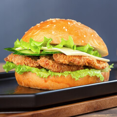 Delicious fresh burger with chicken nuggets and cheese on a wooden table.