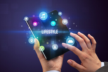 Businessman holding a foldable smartphone with LIFESTYLE inscription, social media concept