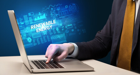 Businessman working on laptop with RENEWABLE ENERGY inscription, cyber technology concept