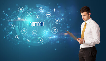 Businessman thinking in front of technology related icons and BIOTECH inscription, modern technology concept