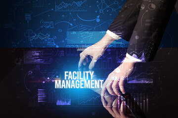 Businessman touching huge screen with FACILITY MANAGEMENT inscription, cyber business concept