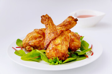 Roasted spicy chicken drumstick with salad on white background.