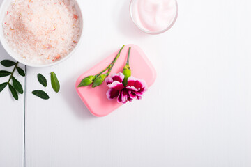 cosmetic cream, soap and bath salt with pink flower, white wood table