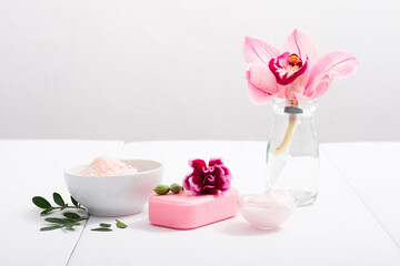cosmetic cream, soap and bath salt with pink flower, white wood table
