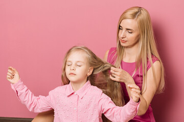 mother with daughter in pink clothes on a pink background