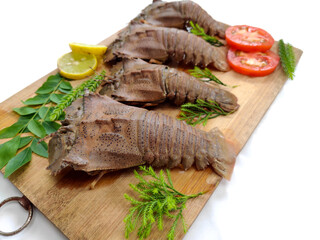 Fresh Sand Lobster or Flathead Lobster or Slipper Lobster (Thenus Orientalis) decorated with herbs and vegetables on a wooden pad.White Background,Selective Focus.