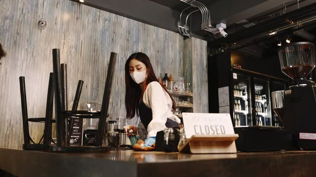 Business owner attractive young couple woman in apron hanging we're open sign on front door  welcoming clients to new cafe. Happy people with protective face mask holding open sign at cafe .