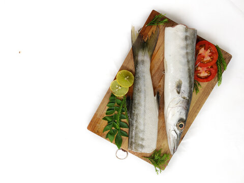 Fresh raw Barracuda Fish (cheelavu) head and body decorated with herbs and vegetables on a White background.Selective Focus.Space for text.