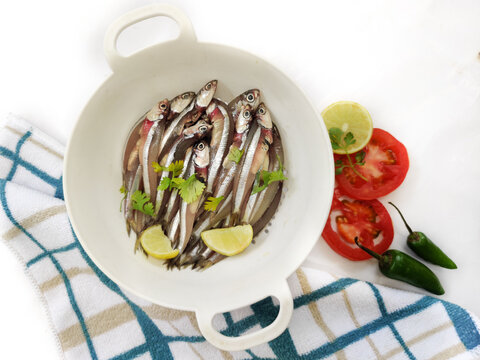 Fresh Anchovy Fish decorated with herbs and vegetables on a white background.Selective focus.