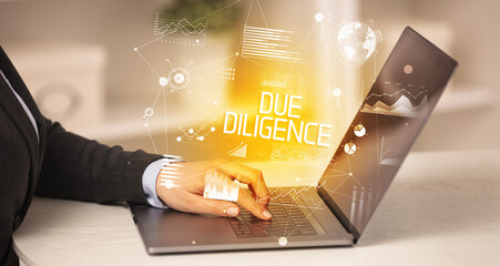 Side view of a business person working on laptop with DUE DILIGENCE inscription, modern business concept